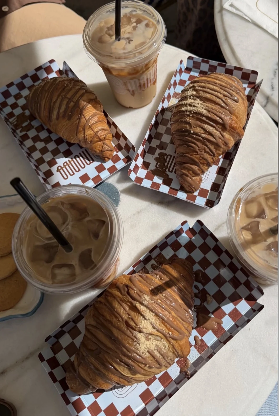 Croissants und Iced Coffee auf gebrandetem Mondo-Papier im Café